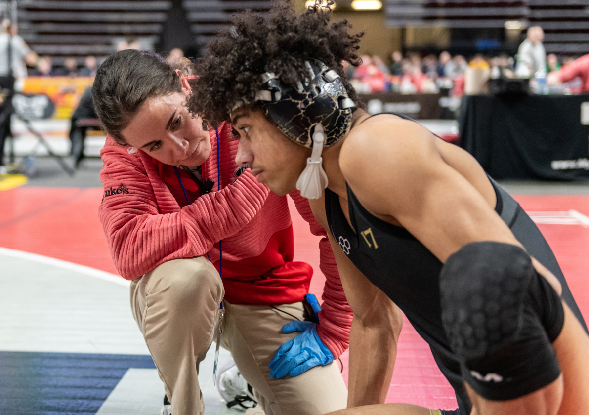 Female athletic trainer talking with wrestling athlete