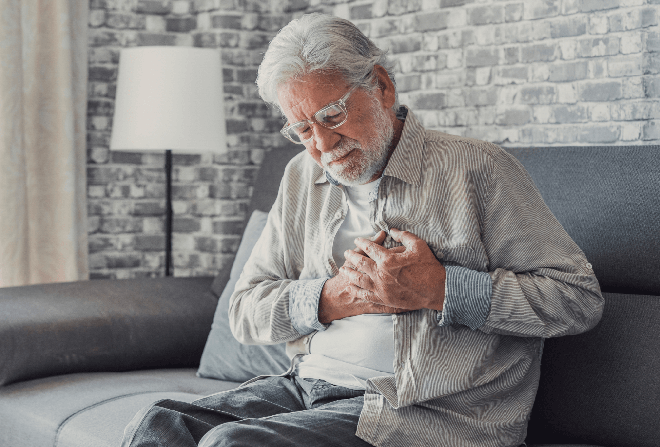 Elderly patient sitting on a couch holding his chest