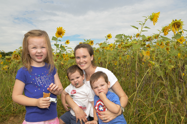 Family enjoys summer storytime - and a snack - in Anderson's sunflower garden