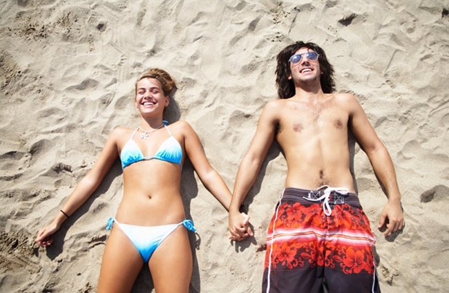Woman and man lying on the beach in swimsuits.