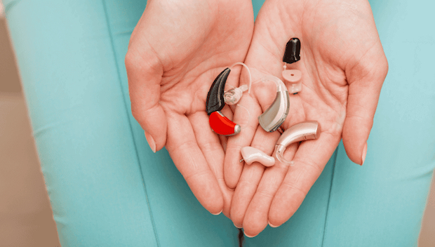 Person displaying different sizes and shapes of hearing aids