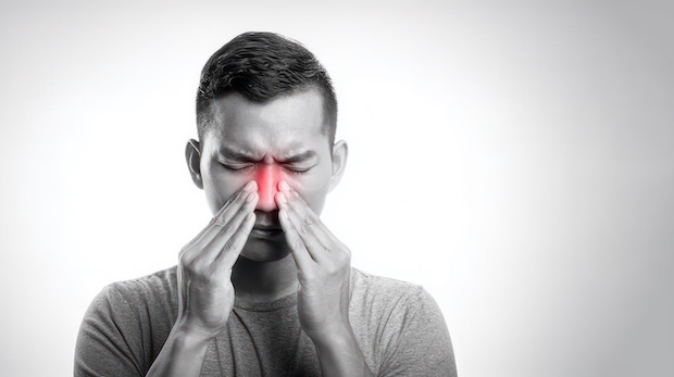 Man holding his nose and suffering from nasal pain and pressure