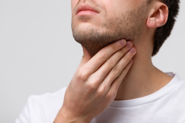 Man holds throat due to discomfort