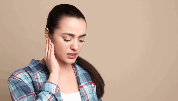 Woman holding ear due to ringing noise