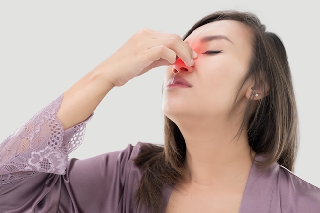 Woman clutching nose due to inflammation