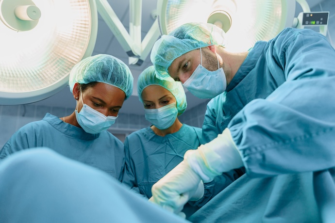 Three surgeons examine a patient