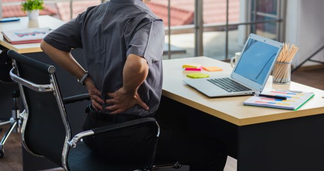 Individual holding their back sitting at their work desk