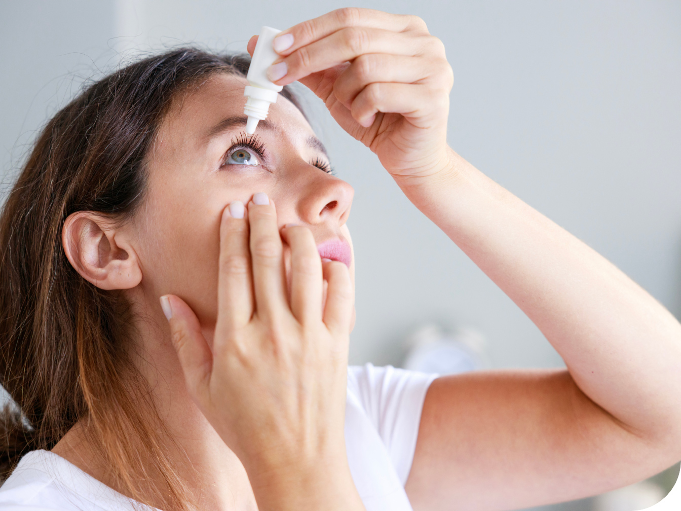 Young woman putting in eye drops