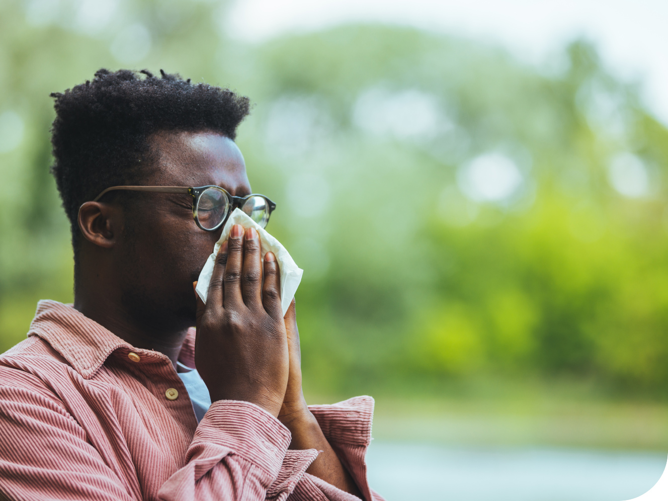 Individual blowing his nose outdoors