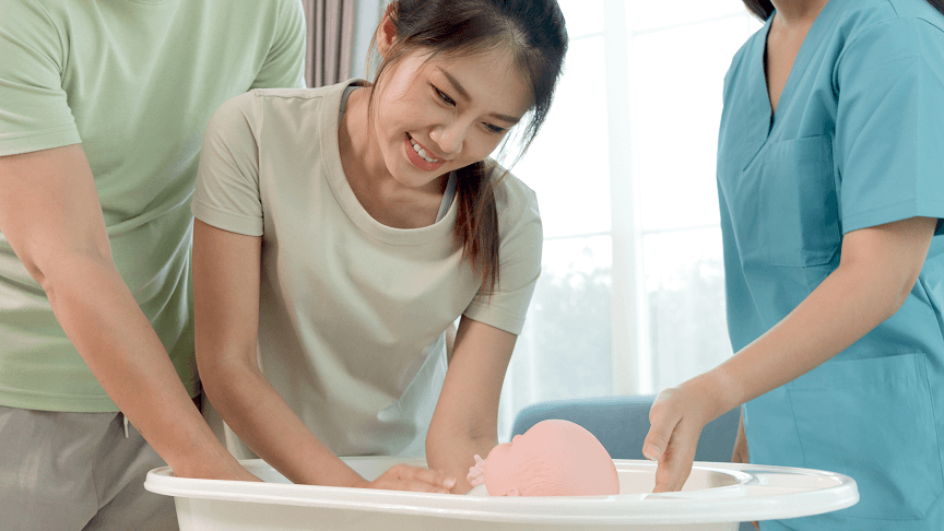 Expecting mother learning how to give a newborn a bath