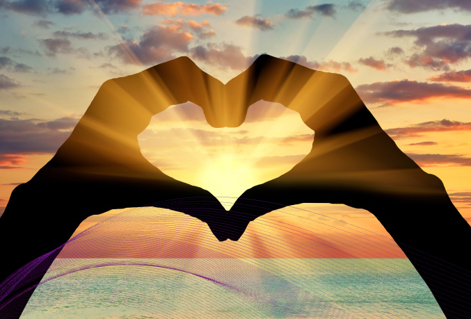 Hands in a heart shape over a sunset