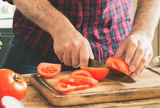 Individual cutting tomatoes on a cutting board