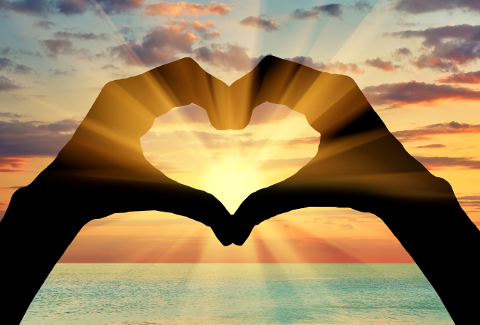 Hands in a heart shape over a sunset