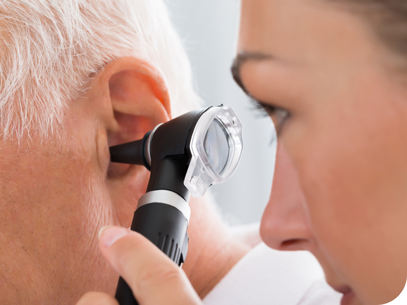 Medical professional looking into an elderly patient's ear