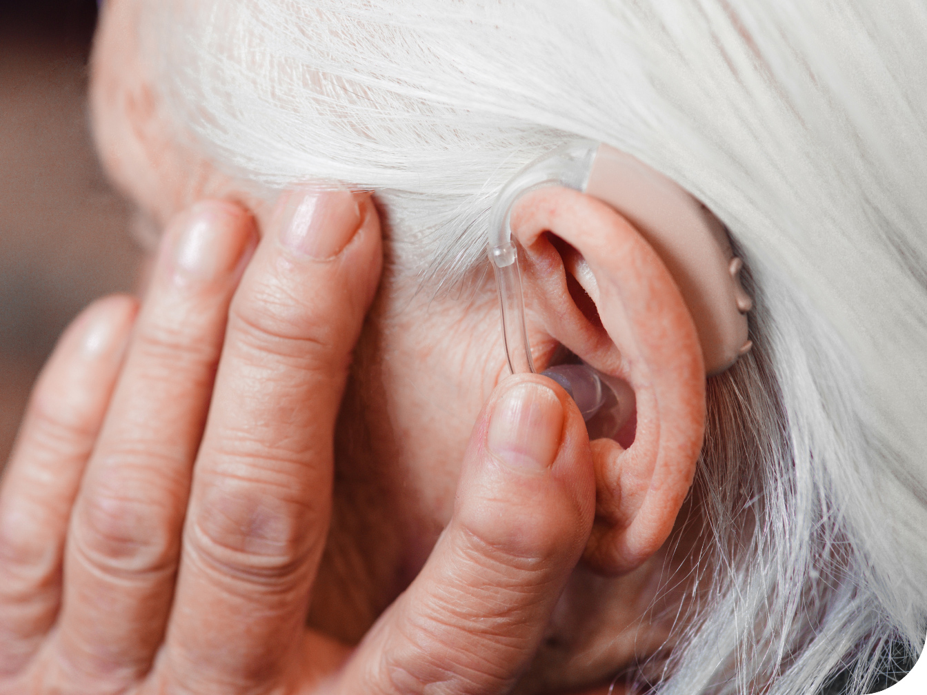 Elderly woman adjusting hearing aid