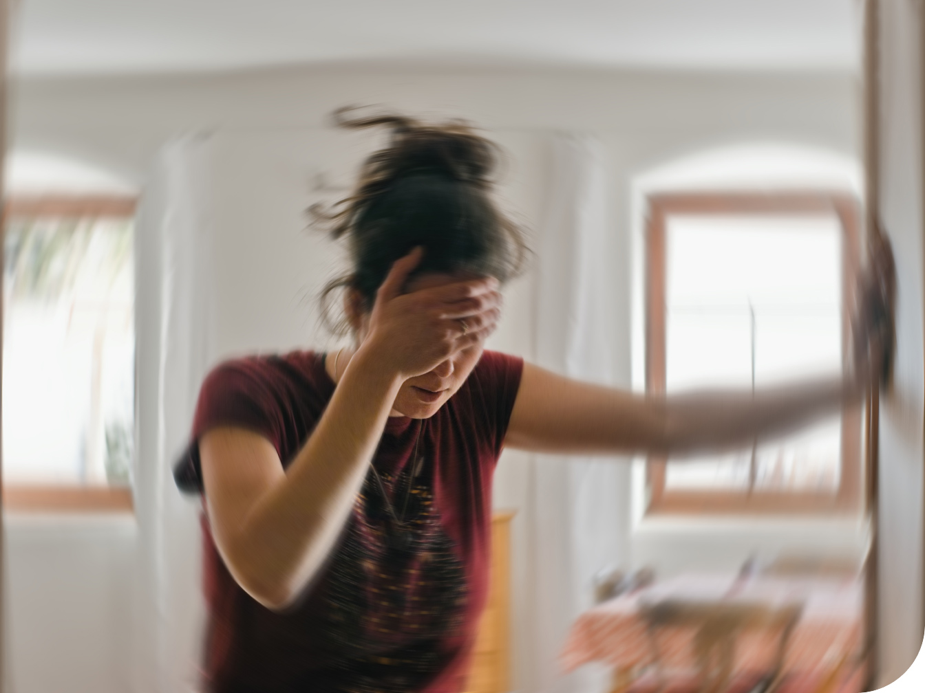 Woman holding her head with her hand in a doorway