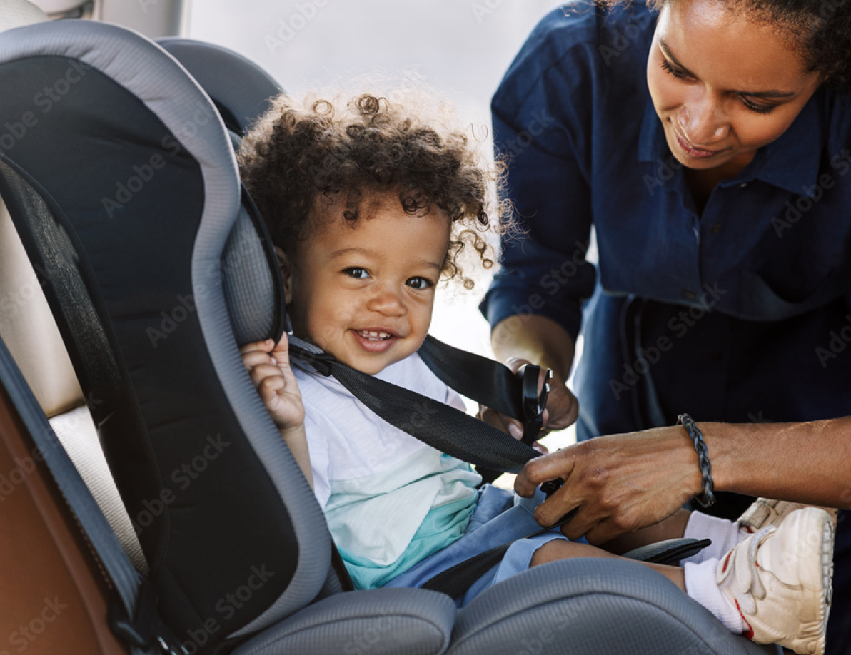 Mom putting young child into a car seat
