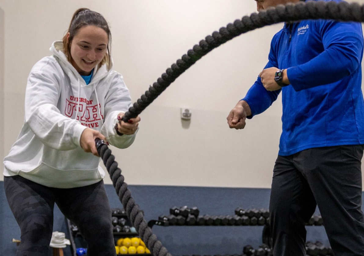 Fitness instructor teaching an individual how to use battle ropes