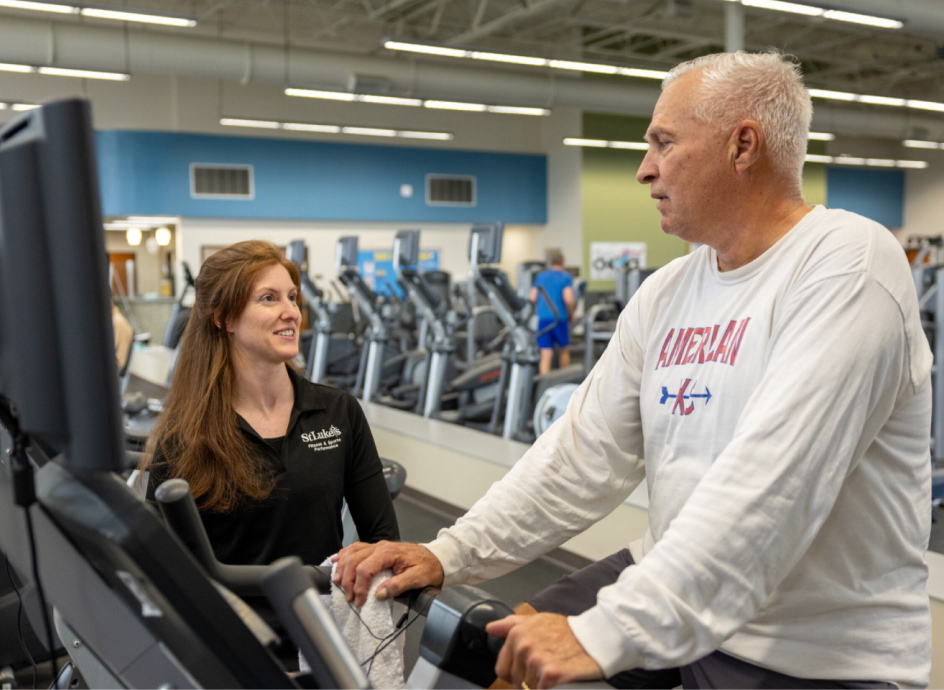 Gym instructor with a member walking on a treadmill