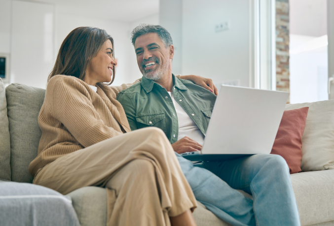 Couple sitting on couch looking at laptop