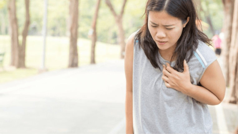 Woman outdoors holding chest