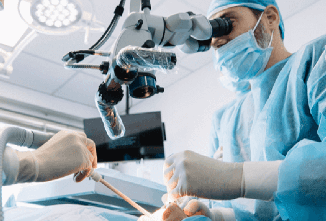 Doctor looking into microscope while working on a patient