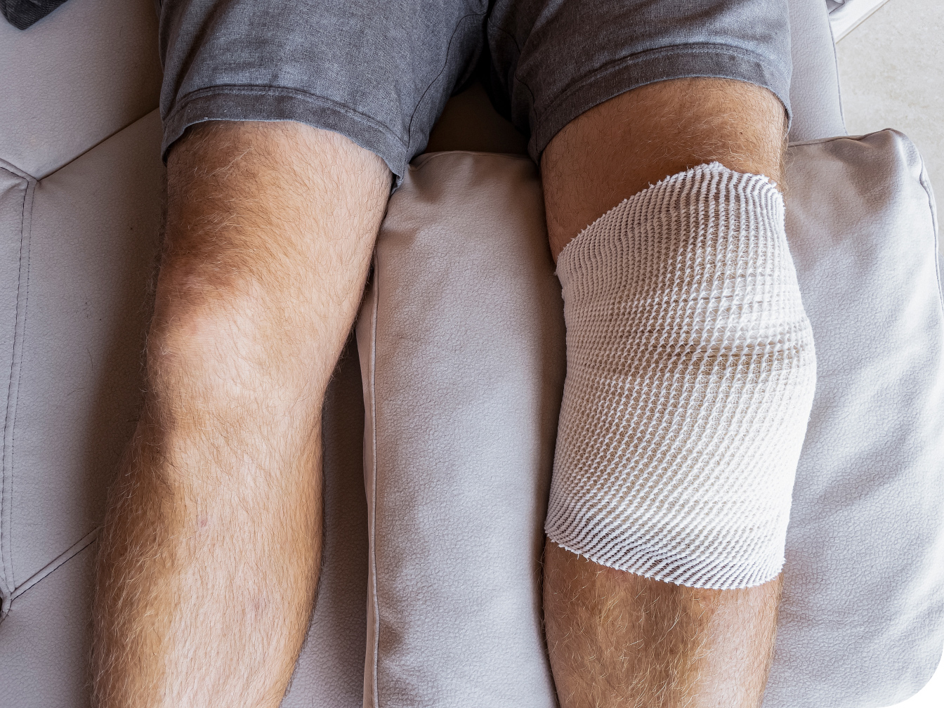 Patient's knee wrapped and elevated on a pillow