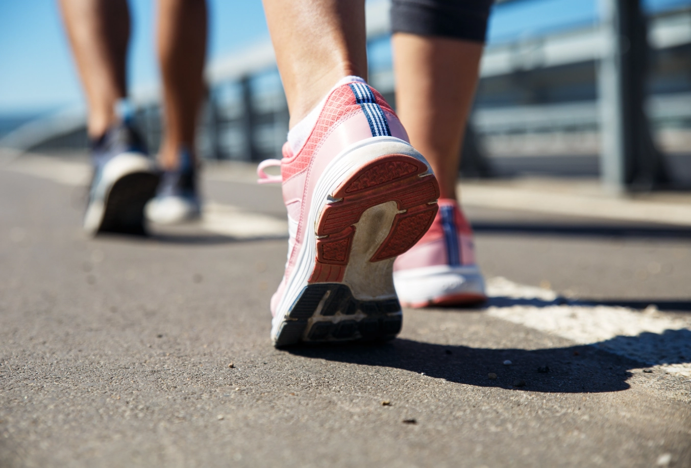 close up of the ankles of 2 individuals running on a road