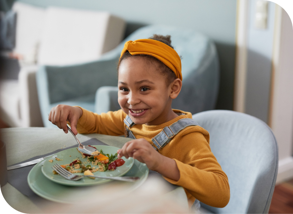 Young girl sitting at a table eating dinner