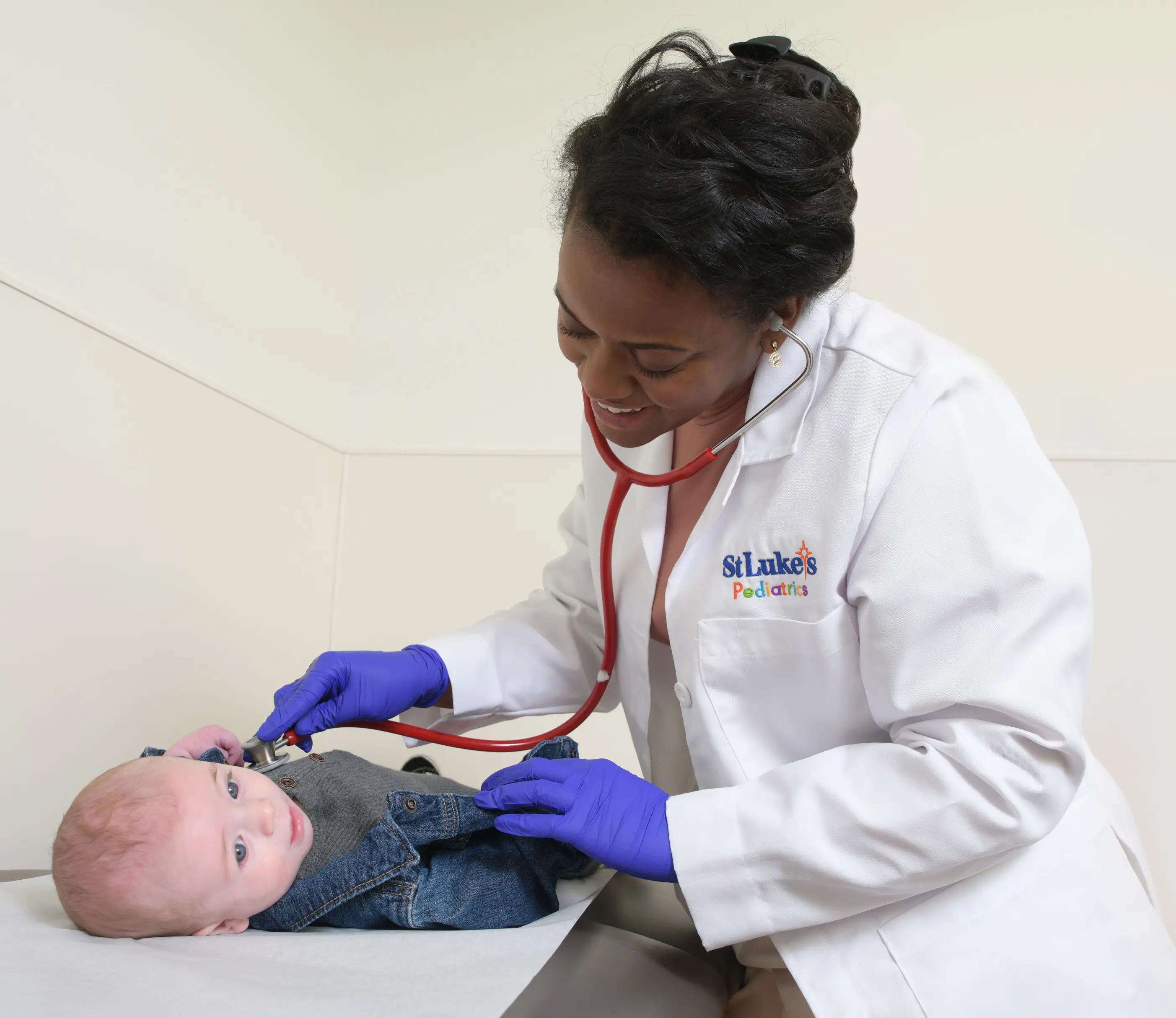 Smiling doctor using a stethoscope on a baby