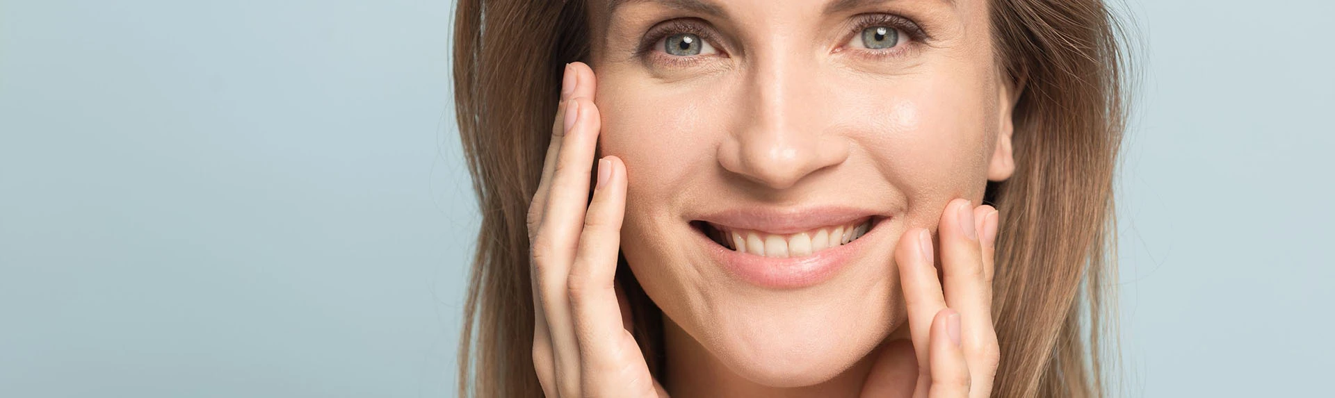 Close up of middle aged woman smiling and touching her face