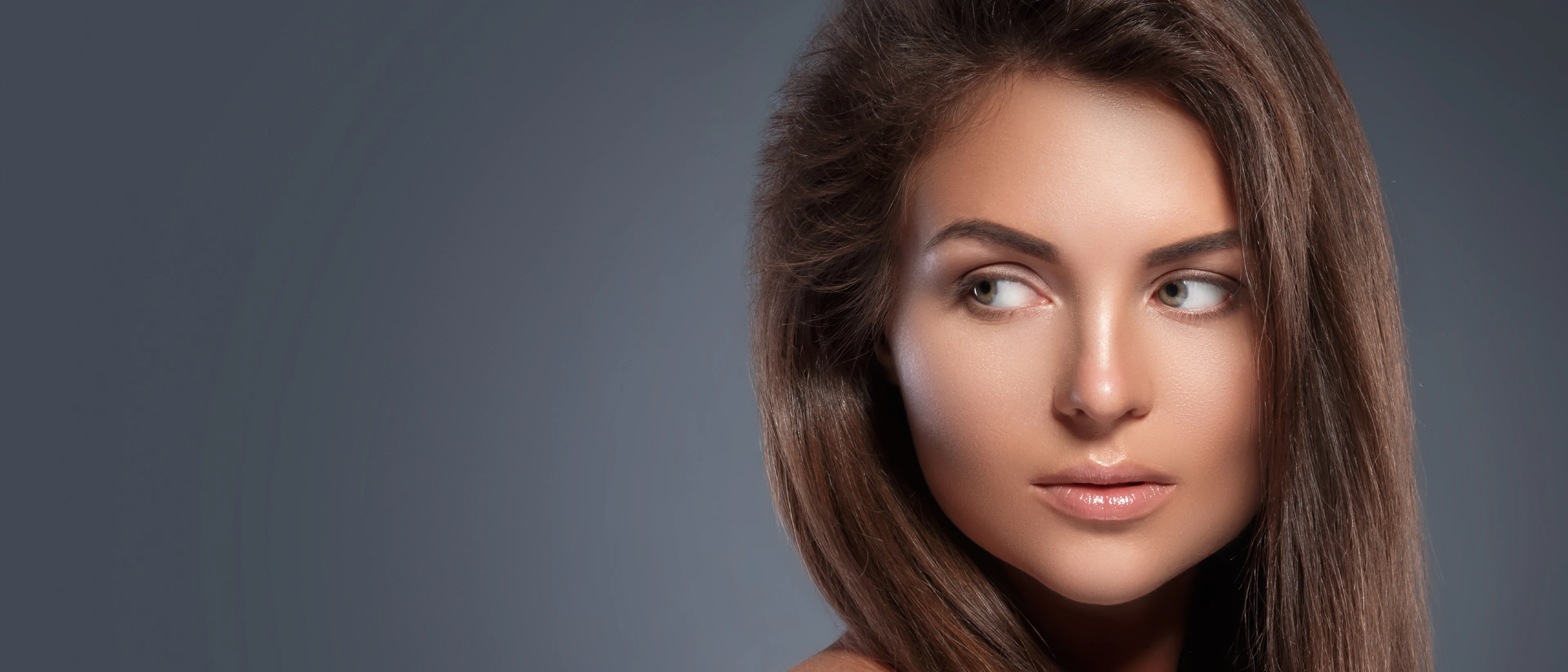 Close up of young brunette woman's face with her eyes looking to the side. 