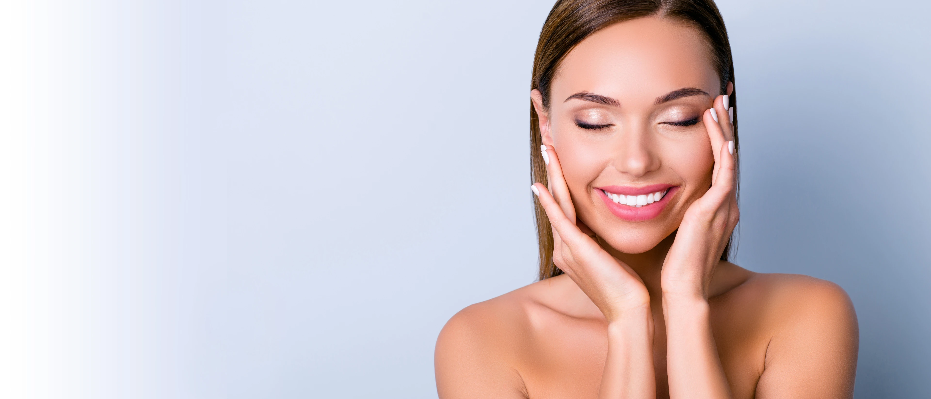 Close up of young woman with her eyes closed, smiling, and her hands on her face