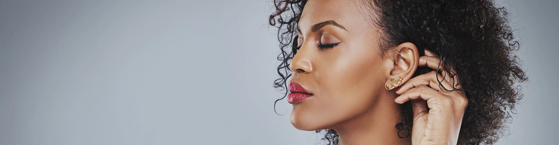 Close up profile of a woman putting on earrings