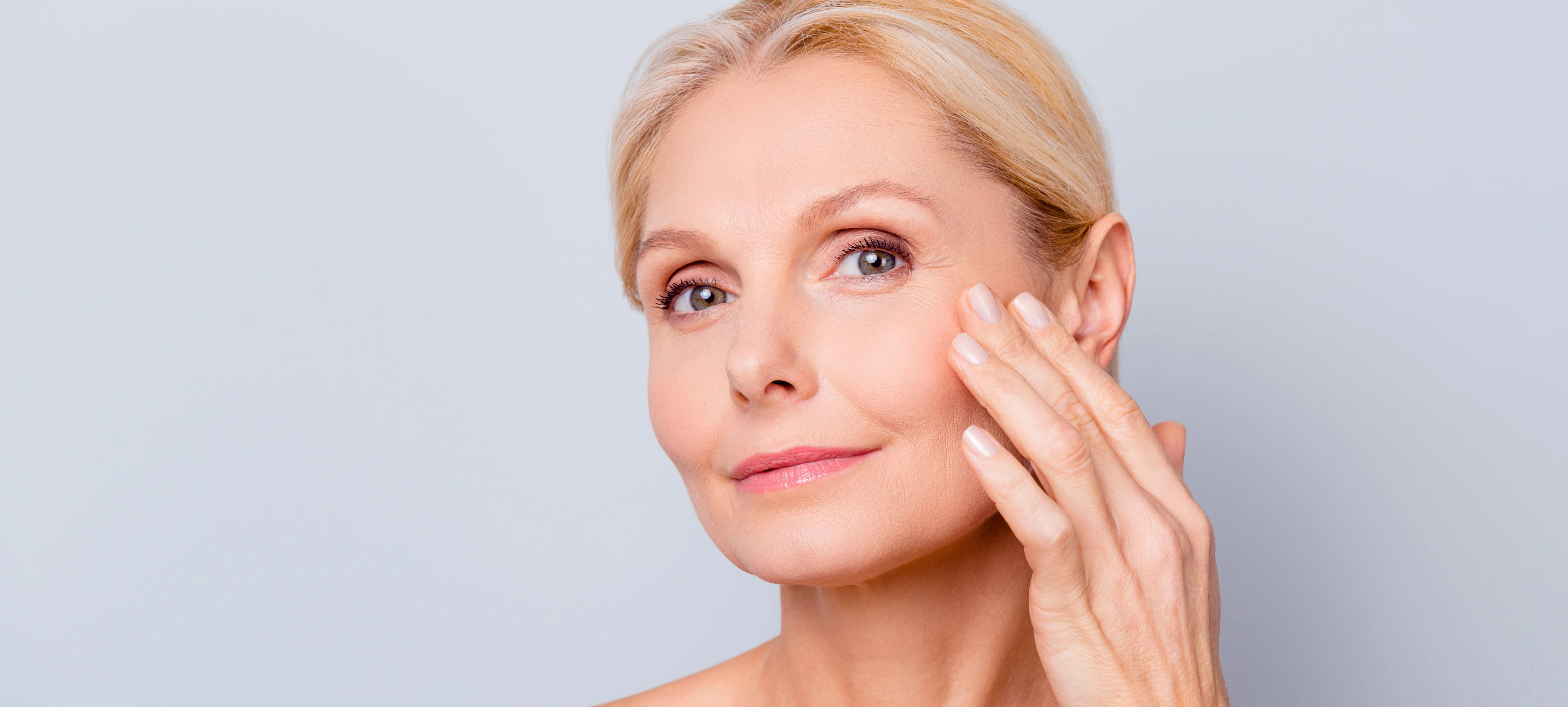 Close up of woman's face while her hand touches around her eye