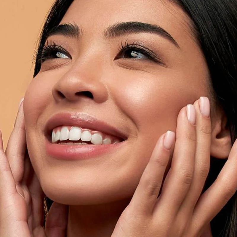 Woman smiling looking up and touching her face with her fingertips