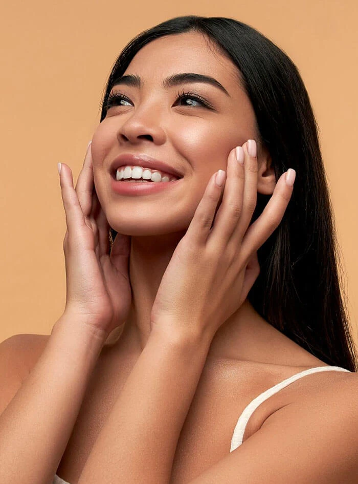 Smiling woman looking up and touching her under eye area