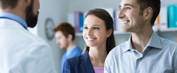 Photo of 2 people smiling while speaking with a doctor