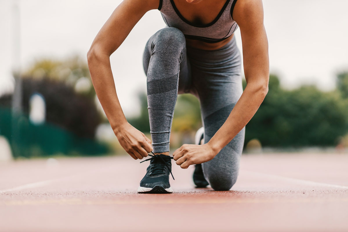 Runner on a track fixing their sneaker