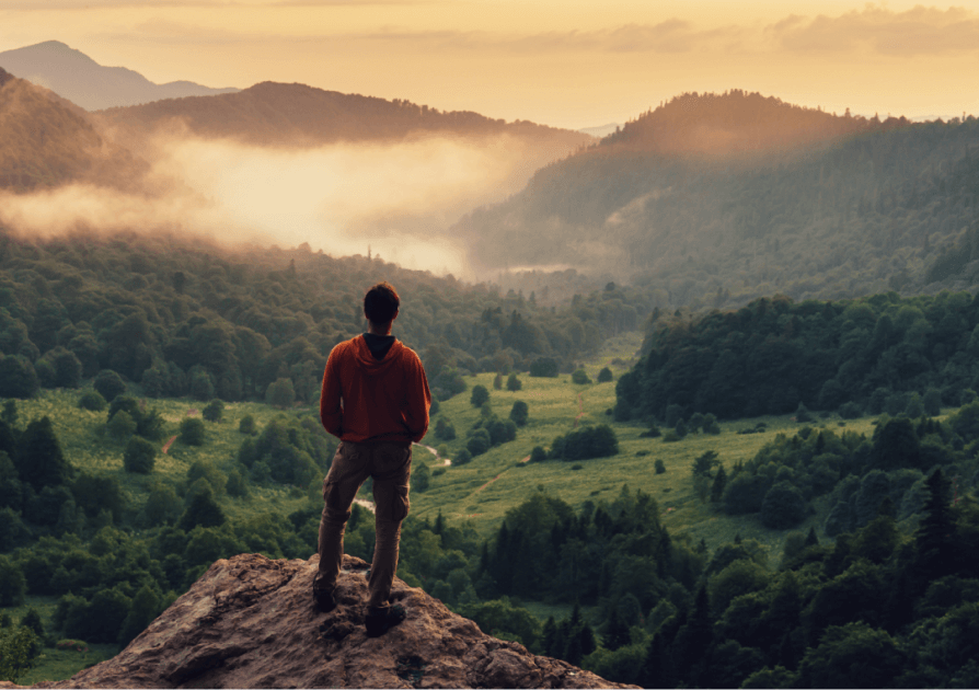 Individual standing on a mountain peak watching the sun rise