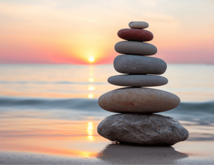 River rock stacked by water at sunset