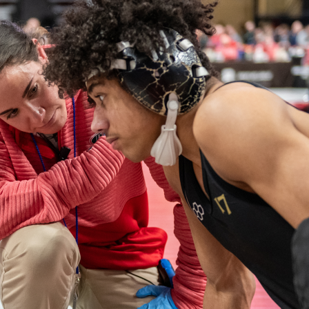 Female athletic trainer talking with wrestling athlete