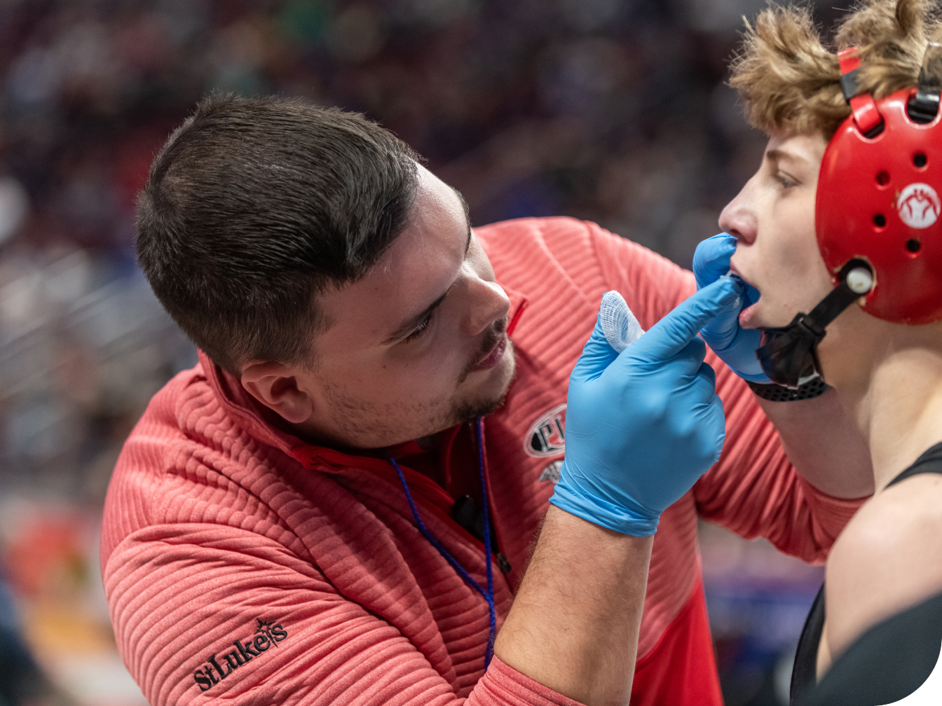 Athletic trainer looking into a wrestling athlete's mouth for injury