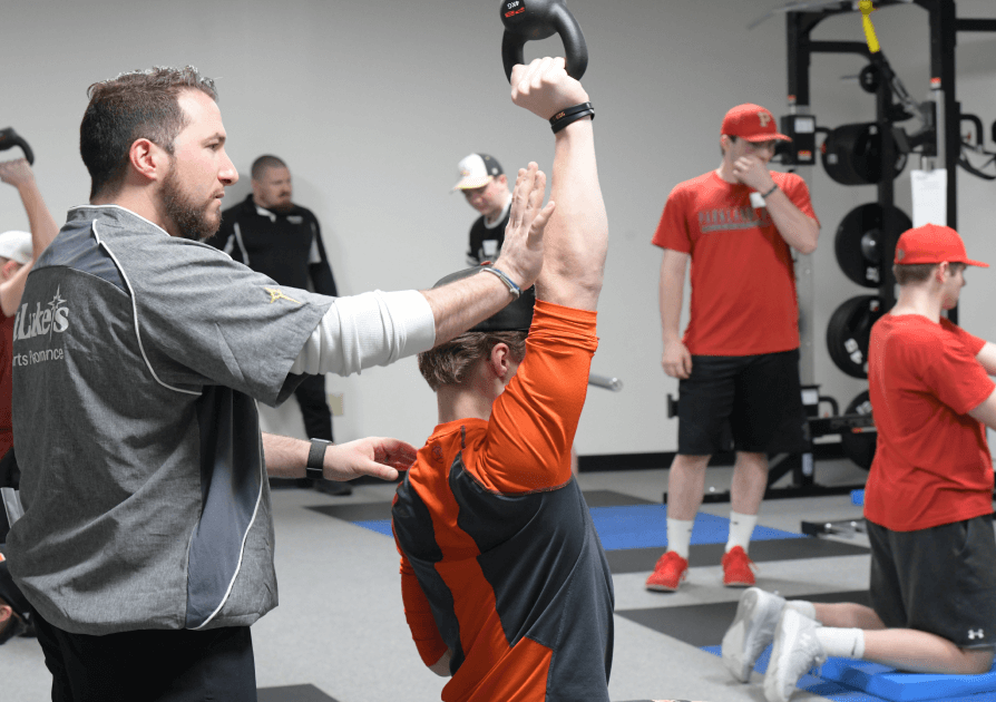 Training coach assisting athletes in the weight room