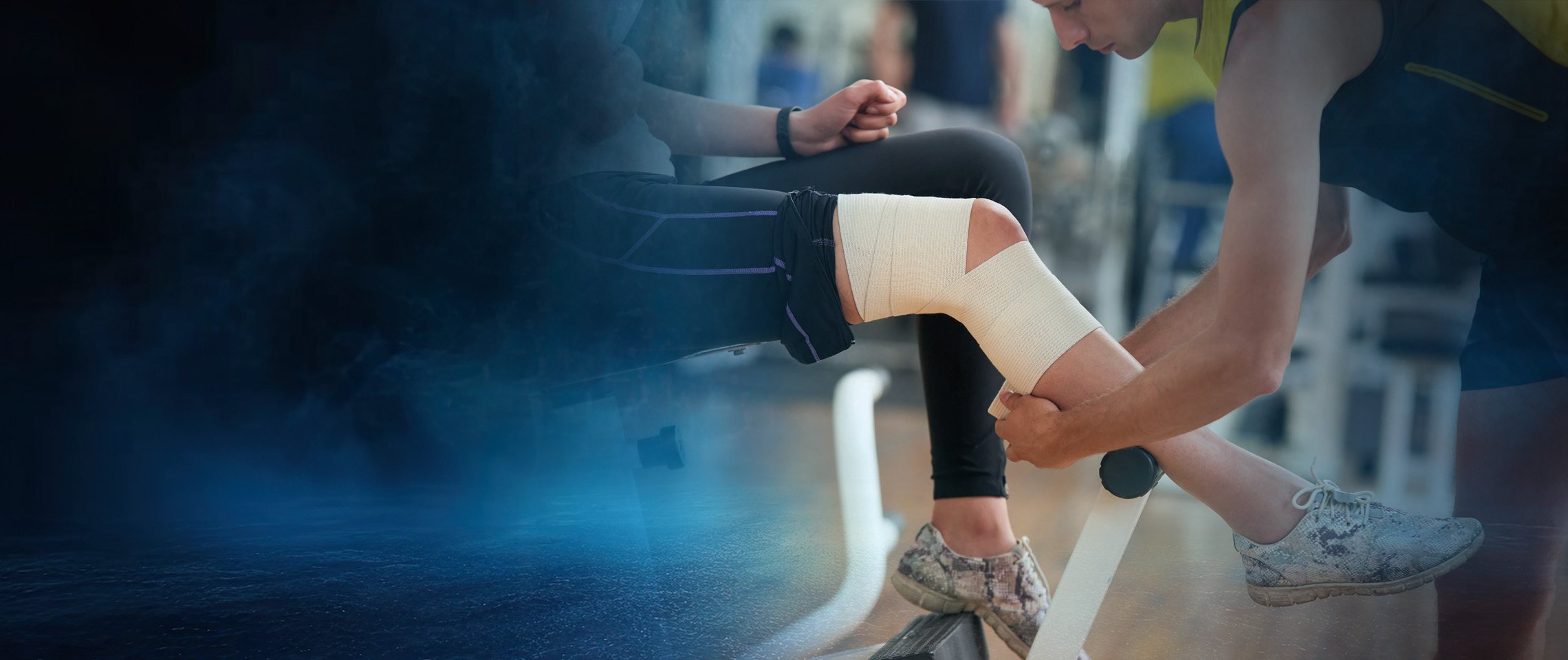 Athletic trainer wrapping an athlete's knee