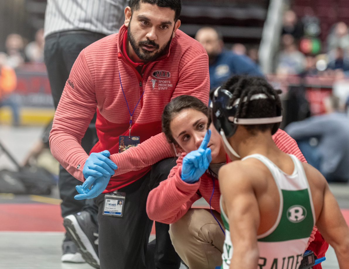 2 athletic trainers assisting a young wrestler