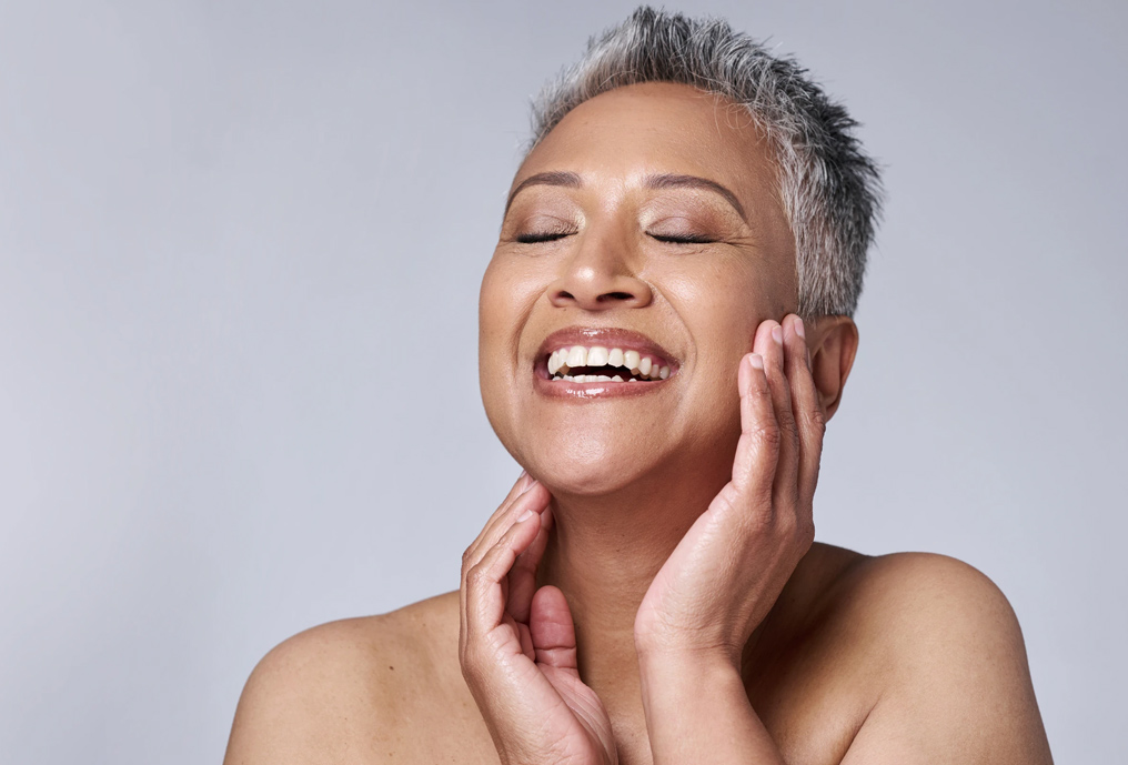 Woman smiling while touching her face