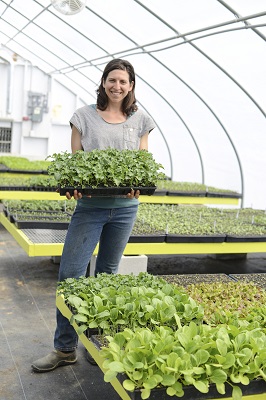 Farmer Lynn in the greenhouse with one of our first crops - kale transplants