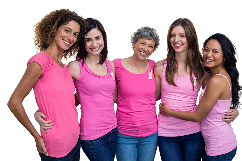 Smiling women in pink outfits posing for breast cancer awareness 