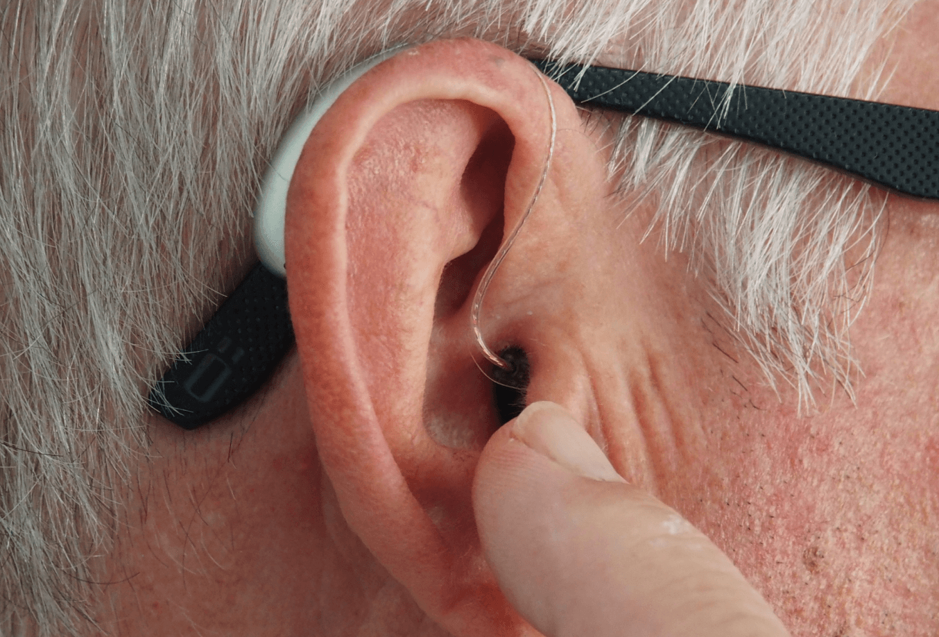 Elderly individual adjusting hearing aid
